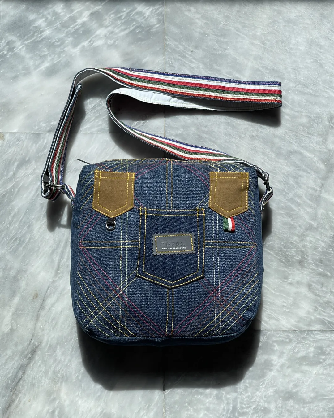 Discover sustainable fashion with this denim crossbody bag crafted from recycled jeans materials. Designed for modern lifestyles it blends durability with unique visual appeal. The patchwork detailing highlights creative stitching patterns that give each piece a distinct character. Its compact shape offers practicality while maintaining a stylish look suitable for everyday use. The adjustable strap provides comfortable wear allowing you to carry it with ease throughout the day. This bag represents conscious fashion choices without compromising on design or function. The deep denim tone is enhanced by contrast stitching that creates a bold and textured appearance. Small accent details add charm and personality making the bag stand out in any setting. The secure zip closure keeps your essentials safe while the interior space is ideal for carrying daily items. The sturdy fabric ensures long lasting use while remaining lightweight and easy to handle. This bag pairs effortlessly with casual outfits adding a touch of originality to your overall style. Perfect for daily errands casual outings or travel this crossbody bag offers both versatility and convenience. It reflects a commitment to sustainable fashion by giving new life to denim materials. You can style it with jeans dresses or simple outfits for a relaxed yet fashionable look. This sustainable denim crossbody bag is more than an accessory it is a statement of creativity responsibility and modern design that fits seamlessly into your lifestyle