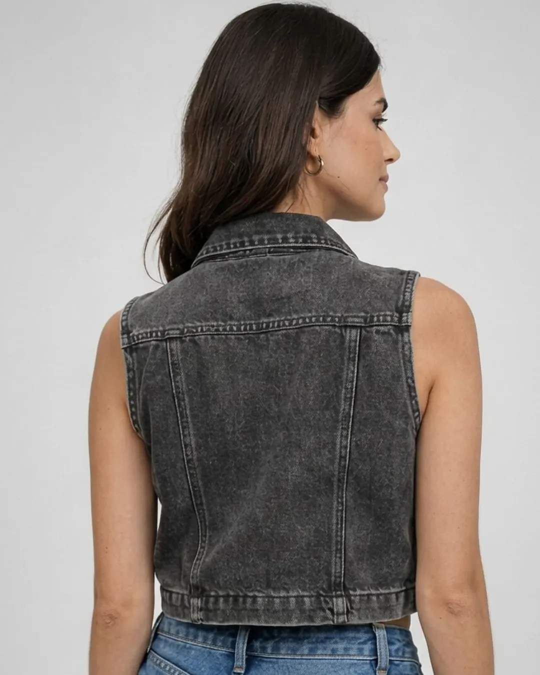Faded black sleeveless denim jacket with cropped fit and button front design. A bold and modern piece that adds effortless style to everyday outfits.